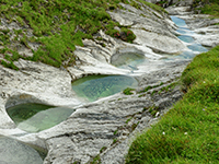 Einige wie an einer Perlenkette aufgereihten Gletschermühlen oberhalb Trin auf der Alp Mora