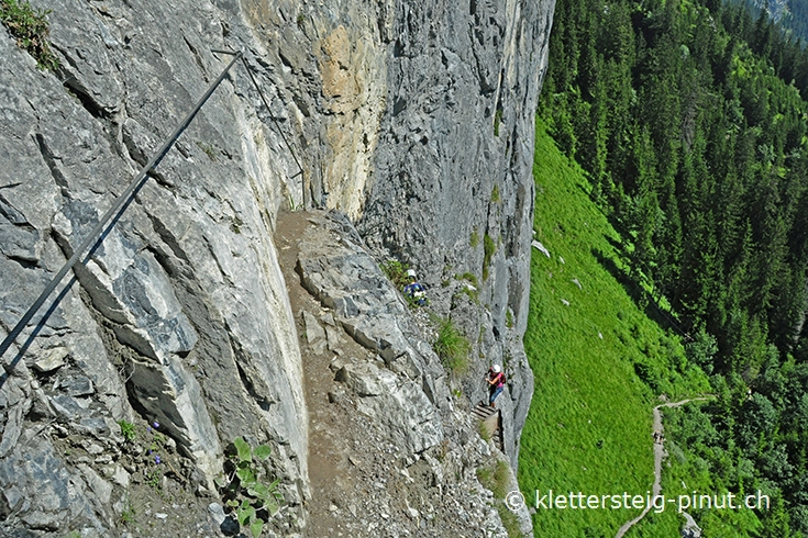 Aufstieg über einen schmaler Felspfad Schmaler Felspfad gesichert mit Stahlseilen beim Klettersteig Pinut