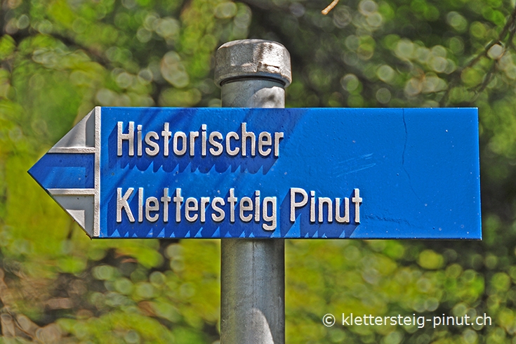 blau-weisser Wegweiser zum Klettersteig Pinut
